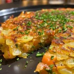Nahaufnahme von Kartoffelrösti mit Kräuterquark auf einem Teller.