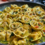 Nahaufnahme einer cremigen Tortellini-Pfanne mit frischem Spinat.