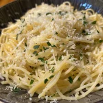 Nahaufnahme von Knoblauch-Parmesan-Pasta mit frischen Kräutern.