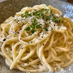 Nahaufnahme von cremiger Knoblauchpasta in einer weißen Schüssel.