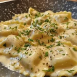 Nahaufnahme von Ravioli Alfredo mit Sahnesauce und Parmesan.