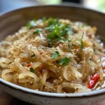 ['Close-up view of Asian potato noodles garnished with herbs and spices.', 'Juicy Asiatische Kartoffelnudeln with visible textures and colors, served in a bowl.', 'Side perspective of a plate featuring delicious Asian-style potato noodles, herbs, and toppings.', 'Detailed image of homemade potato noodles with garlic, chili flakes, and sesame seeds.']