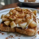 ['Close-up view of delicious apple pie toast topped with cinnamon apples and yogurt.', 'Side view of a toast slice featuring warm spiced apple filling and creamy yogurt.', 'Appetizing apple pie toast with diced apples, almond butter, and cinnamon on a toasted slice of bread.', 'Tasty apple pie toast garnished with plain yogurt and a drizzle of almond butter on a golden toast.']
