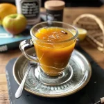 ['Close-up view of a bowl of homemade Apfelkompott with visible apple chunks.', 'Side view of a glass filled with warm Apfelkompott, garnished with a sprinkle of cinnamon.', 'Juicy apple compote in a clear dish, showcasing its texture and vibrant color.', 'A bowl of Apfelkompott with a spoon, highlighting the deliciousness of the dish.']