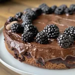 ['Side view of a dark chocolate blackberry cake with fresh blackberries on top.', 'Close-up shot of a rich dark chocolate cake layered with blackberry frosting.', 'Juicy dark chocolate blackberry cake seen from the side, showcasing its layers.', 'A luscious slice of dark chocolate cake adorned with blackberries and frosting.']