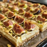 ['A side view of Honey Fig Cheesecake Bars topped with fresh figs and pistachios.', 'Close-up of creamy cheesecake bars with honey and figs, showcasing the textured layers.', 'Dessert photograph featuring cheesecake bars with a golden crust and fig slices on top.', 'View of rich cheesecake bars adorned with nuts and honey, highlighting the fresh fig topping.']