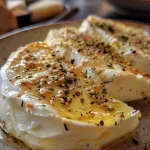 ['Close-up view of a baked Hokkaido squash with feta cheese and herbs.', 'Juicy, roasted Hokkaido pumpkin garnished with thyme and honey.', 'Side profile of Ofen-Hokkaido with melted feta and sesame oil drizzle.', 'Appetizing shot of a stuffed Hokkaido squash showcasing its golden color.']
