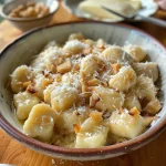 ['A close-up view of gnocchi served with pears and dried figs.', 'Juicy gnocchi dish featuring sliced pears and figs, styled attractively.', 'Side view of delicious gnocchi topped with fresh ingredients, including pears.', 'A detailed shot of gnocchi with a rich, textured sauce and garnishes.']