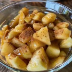 ['Close-up view of creamy apple pie dip in a small bowl, garnished with sautéed apples and granola.', 'Side angle of a delicious apple pie dip, showcasing a smooth texture with toppings.', 'Appetizing apple pie dip presented in a bowl, topped with granola and cooked apple pieces.', 'Creamy and inviting apple pie dip with a rich color, adorned with chopped apples and granola on top.']