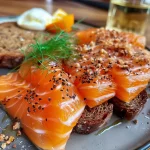 ['Close-up view of Färöer Lachs with a crust made of Lebkuchen and Pumpernickel.', 'Side shot of beautifully plated Färöer Lachs garnished with herbs and spices.', 'Juicy piece of salmon topped with a spiced bread crust, ready to serve.', 'Delicious Färöer Lachs with a decorative crust, showcasing vibrant colors and textures.']
