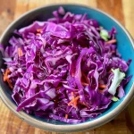['Close-up of vibrant red and green shredded cabbage mixed with julienned carrots.', 'Juicy fermented red cabbage with green cabbage and carrots, showcasing textures.', 'Side view of a colorful mix of fermented red and green cabbage with carrots.', 'Detailed shot of raw sauerkraut with different vegetables highlighted.']