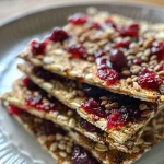 ['A close-up view of a Frischkäse-Cranberry-Cracker topped with cranberry jam and parsley.', 'Side angle photo of a delectable Frischkäse and cranberry cracker, showcasing its vibrant toppings.', 'Detailed close-up of a cracker spread with creamy Frischkäse and adorned with red cranberry sauce.', 'A side view of a delicious Frischkäse-Cranberry-Cracker, highlighting fresh parsley and vibrant colors.']
