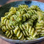 ['Close-up view of gluten-free vegan pumpkin pesto with pasta.', 'Side angle of vibrant pumpkin pesto mixed with gluten-free pasta.', 'Juicy gluten-free vegan pumpkin pesto plated with Casarecce pasta.', 'Detailed look at creamy pumpkin pesto alongside gluten-free pasta.']