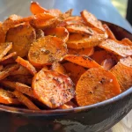 ['Close-up view of crispy carrot chips with a golden-brown color.', 'Thinly sliced carrot chips arranged attractively, showcasing their texture.', 'A side view of crunchy carrot chips, highlighting their spiced seasoning.', 'A vibrant plate of homemade carrot chips, emphasizing their crispy edges.']
