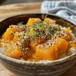 ['Close-up view of a bowl of Korean pumpkin porridge with rice dumplings.', 'Side view of a creamy kabocha porridge topped with small rice dumplings.', 'Delicious Korean pumpkin porridge served in a bowl with a spoon beside it.', 'Warm, inviting bowl of pumpkin porridge with colorful rice dumplings.']