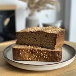 ['Close-up shot of Kürbis Brot showcasing a golden-brown crust and visible pumpkin seeds.', 'Side view of a loaf of Kürbis Brot, highlighting its texture and the vibrant color of pumpkin puree.', 'Detailed view of freshly baked Kürbis Brot with a rich, inviting crust and sprinkled pumpkin seeds on top.', 'A slice of Kürbis Brot displayed on a wooden board, revealing the moist interior with pumpkin puree.']