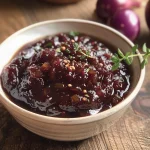['Close-up view of Trauben-Zwiebel-Chutney in a glass jar with fresh ingredients around.', 'Side photo of Trauben-Zwiebel-Chutney showcasing its rich texture and color.', 'Juicy Trauben-Zwiebel-Chutney displayed in a bowl with grapes and onions nearby.', 'Freshly made Trauben-Zwiebel-Chutney alongside its key ingredients on a wooden surface.']
