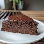 ['A side view of a vegan chocolate sweet potato cake with rich chocolate frosting.', 'Close-up of a moist chocolate cake topped with sweet potato frosting, displayed on a plate.', 'A slice of vegan chocolate cake featuring a creamy sweet potato frosting, captured in natural light.', 'A decadent vegan cake layered with sweet potato frosting, showcasing its rich texture and color.']