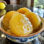 Close-up of homemade Quittengelee in a jar with fresh quinces nearby.